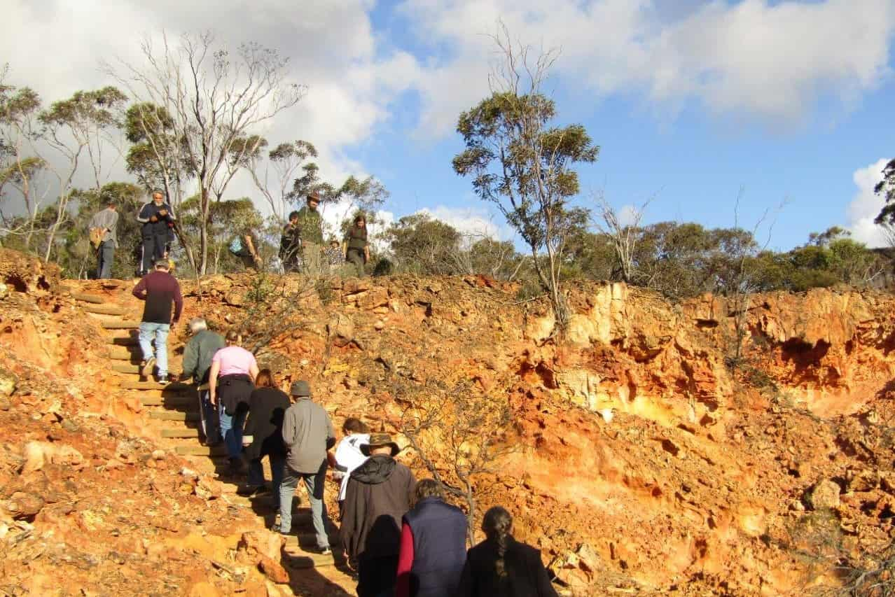 Line of people walking up red rocky ridge