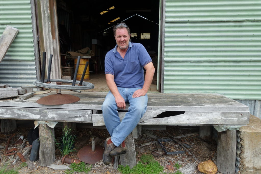 Man sitting on edge of abandoned shearing shed