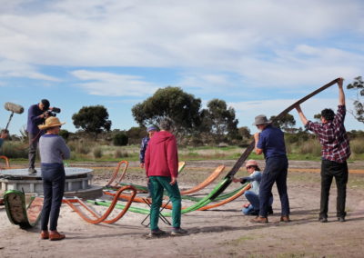 Group of people working together to slide artwork into the metal frame of the Gondwana Link sculpture