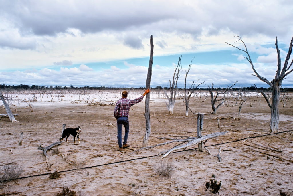 Image of Kingsley with his dog Gabby, . beside a hyper-saline lake bed— a result of the land clearing years. Picture: Frank Rijavec.